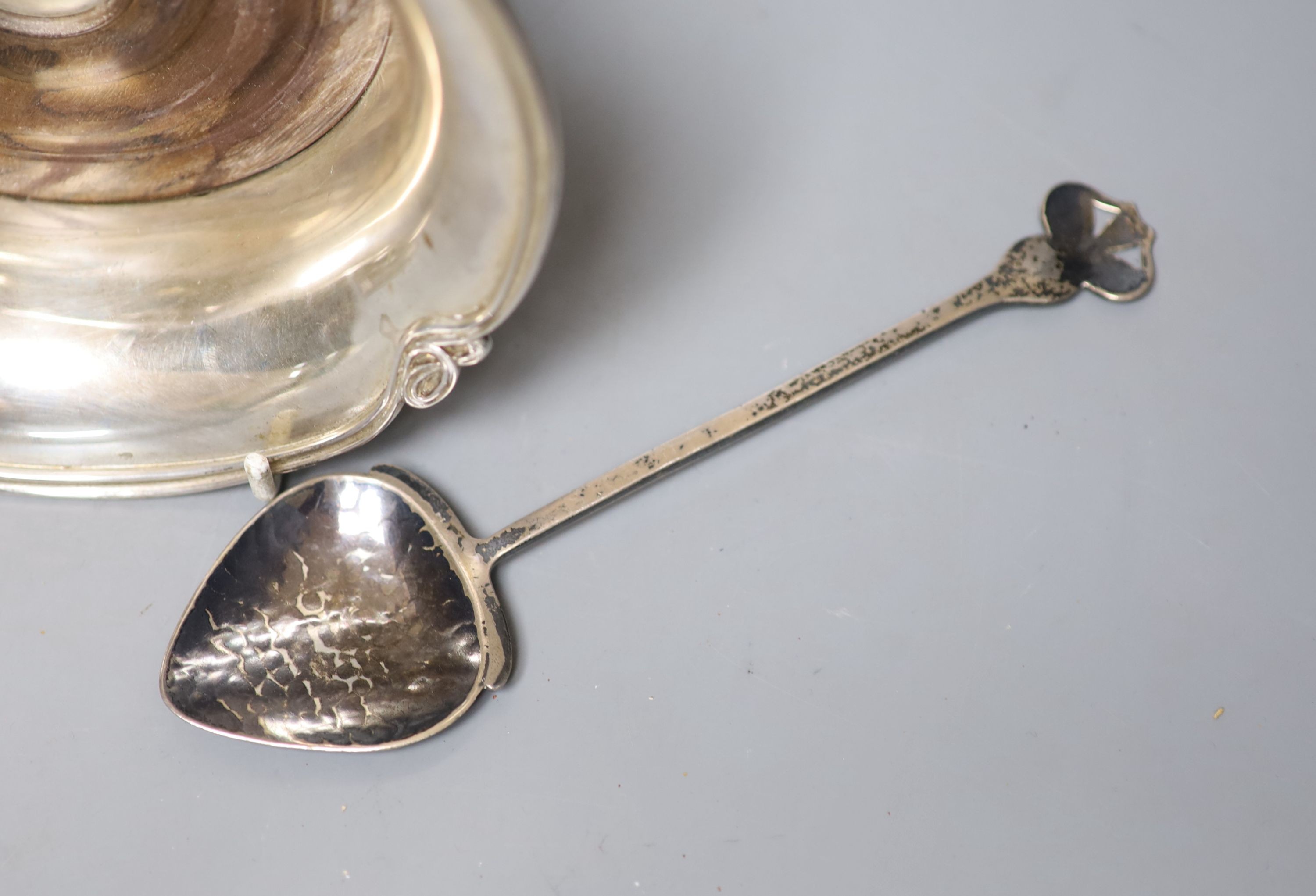 A George V Art Nouveau silver spoon, D & M Davis, Birmingham, 1911, 18.2cm, together with a modern silver mounted wine coaster and a silver napkin ring.